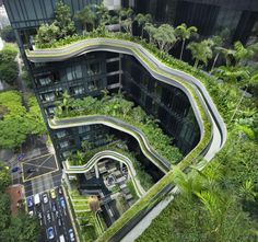 an aerial view of a building with green vegetation growing on the side of it and cars driving down the street