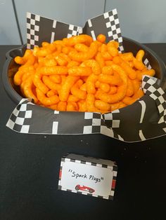 a bowl filled with cheetos sitting on top of a table next to a card