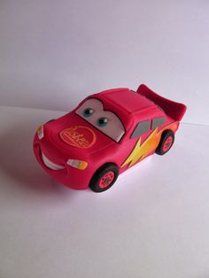 a red toy car sitting on top of a white table