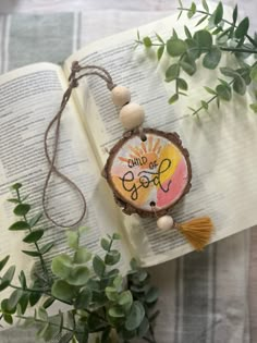 an open book with a tassel on it next to some plants and greenery