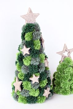 a small green christmas tree next to a smaller one with silver stars on it's top