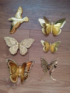 several different types of butterflies on a wooden surface with one gold, the other silver