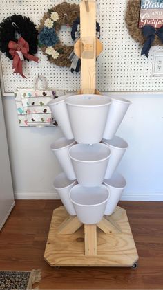 a stack of white cups sitting on top of a wooden stand in front of a wall