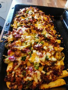 a pan filled with cheesy french fries covered in cheese and toppings on top of a stove