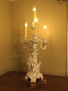 an angel figurine on a wooden table with candles in the corner behind it