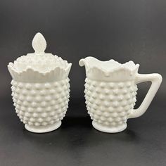 two white vases sitting next to each other on a table