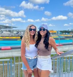 two women standing next to each other near a fence