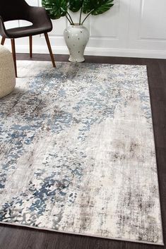 a white and blue area rug in a living room with a plant on the floor