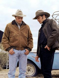 two men standing next to each other in front of a blue pick - up truck