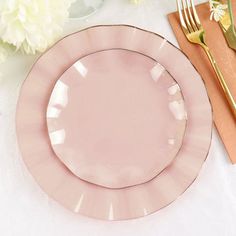 a pink plate sitting on top of a table next to a knife and fork with flowers in the background