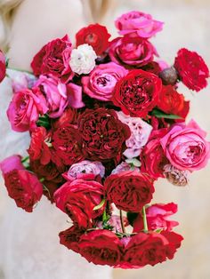 a woman holding a bouquet of red and pink flowers