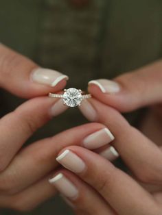 two hands with white manies holding an engagement ring