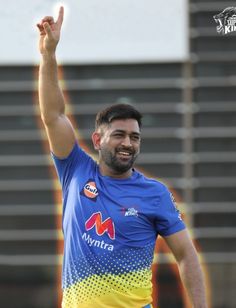 a man in blue and yellow jersey throwing a ball with his hand up to the sky