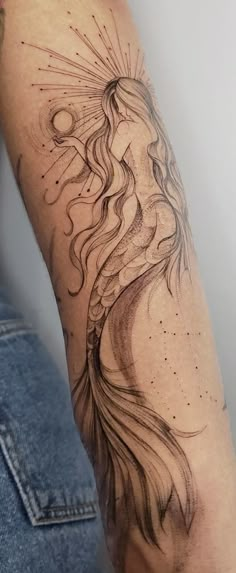 a woman's arm with a tattoo on it and sun rays coming out of her hair