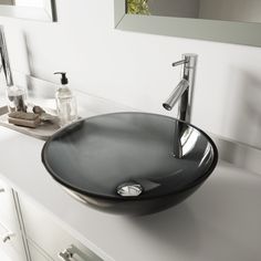 a black bowl sink sitting on top of a white counter next to a bathroom mirror