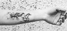 a black and white photo of a person's arm with horse tattoos on it