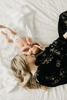 a woman laying on top of a bed next to a baby