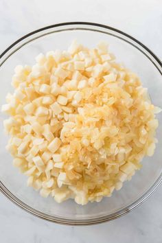 chopped potatoes in a glass bowl on a marble counter top, ready to be cooked