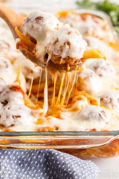 a spoon full of pasta and meatballs being lifted from a casserole dish