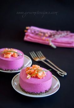 two small cakes on plates with forks and napkins next to each other in front of a black table