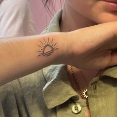 a woman with a small sun tattoo on her arm