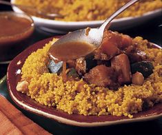 a plate filled with rice and meat covered in gravy next to other dishes