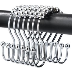 a bunch of metal balls hanging from the side of a black curtain rod on a white background