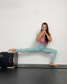 a woman standing on one leg and holding her hands up in the air while stretching