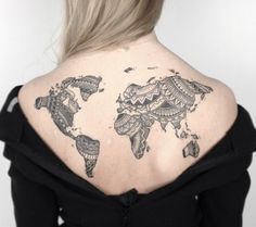 the back of a woman's shoulder with a world map tattoo on her upper arm