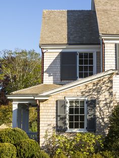 the house is made of wood and has shutters on each side, along with two windows