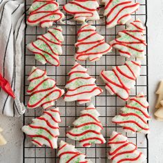 christmas cookies decorated with white and red icing on a cooling rack