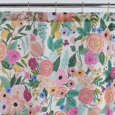 the shower curtain is decorated with colorful flowers and green leaves on white background, hanging from a metal rod