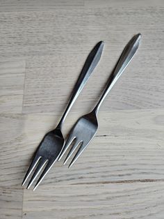 two forks on a wooden table with one fork stuck in the other's side