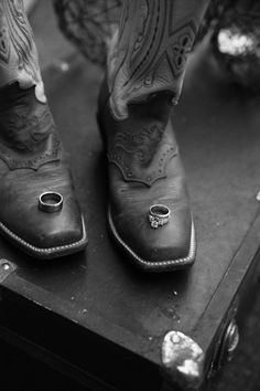 black and white photograph of cowboy's boots with wedding rings on the soles