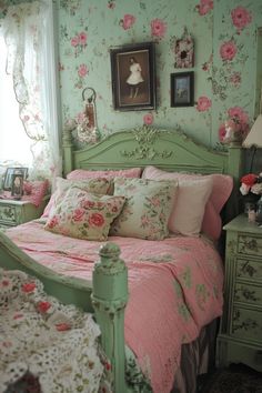 a green bed with pink flowers on the wall and pictures hanging above it's headboard