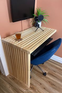 a wooden desk with a blue chair and a flat screen tv mounted on the wall