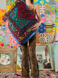 a woman standing in front of a wall covered with quilts and other colorful items