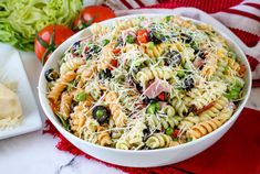 a bowl filled with pasta and vegetables on top of a red towel next to some bread