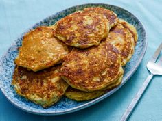 some pancakes on a blue and white plate with a fork next to it, ready to be eaten