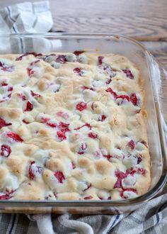 a casserole dish with strawberries and cream in it on a plaid cloth