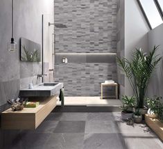 a modern bathroom with grey tiles on the walls and floor, along with potted plants