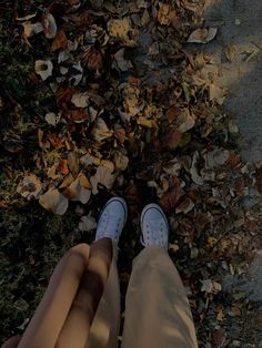 the person is standing in front of leaves on the ground with their feet propped up