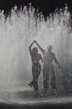 two people standing in front of a fountain with water spewing from the sides