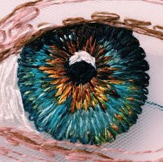 an eyeball is shown in this artistic photograph with colored thread on it and the iris visible