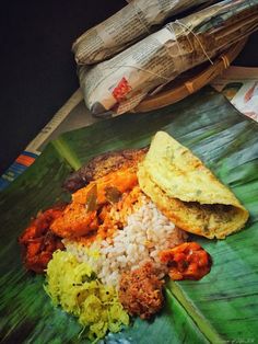 rice, meat and vegetables on a banana leaf next to some newspapers in the background