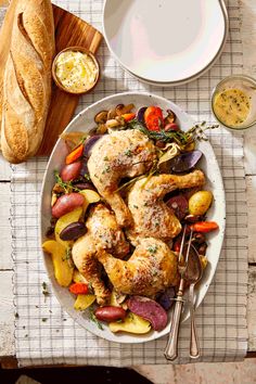 a white plate topped with chicken and veggies next to a loaf of bread