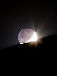 the moon is shining brightly in the dark sky