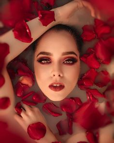 a woman is surrounded by roses and petals