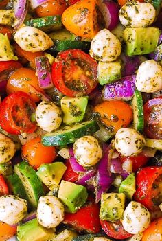 a close up view of a salad with tomatoes, cucumbers and other veggies