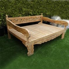 a wooden bed sitting on top of a lush green field